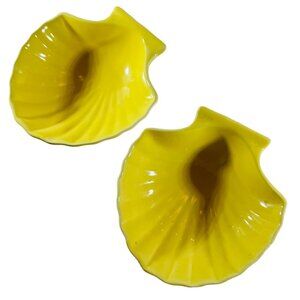 Two Little bright yellow clam shell dishes, sushi, sauces, kitty food.